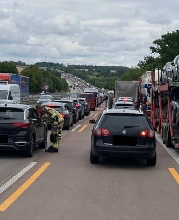 Einsatzkräfte der Feuerwehr gehen von Auto zu Auto, um auf die Rettungsgasse hinzuweisen.