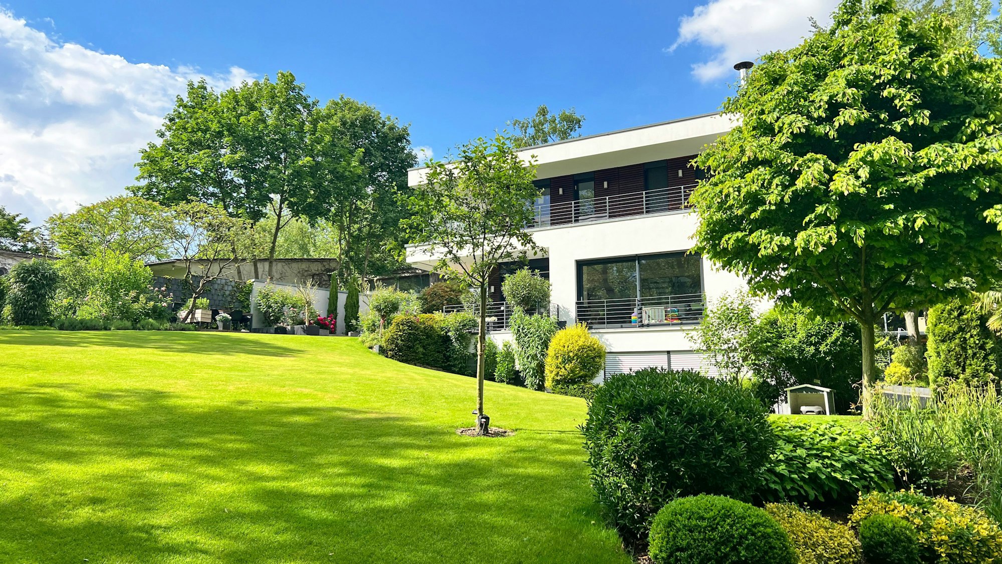 Am Hang gelegene Gartenanlage mit Haus im Hintergrund