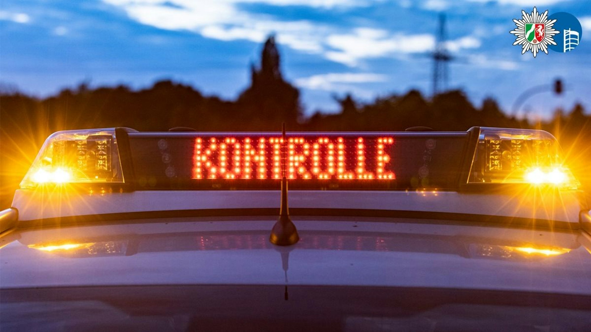 Ein Roller steht am Straßenrand, im Hintergrund ein Polizeiwagen.