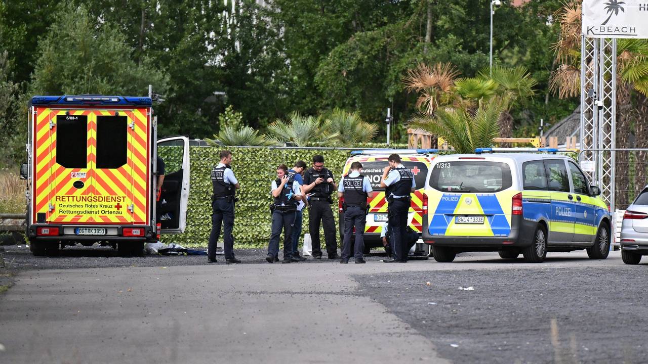 Einsatzkräfte stehen an ihren Fahrzeugen.