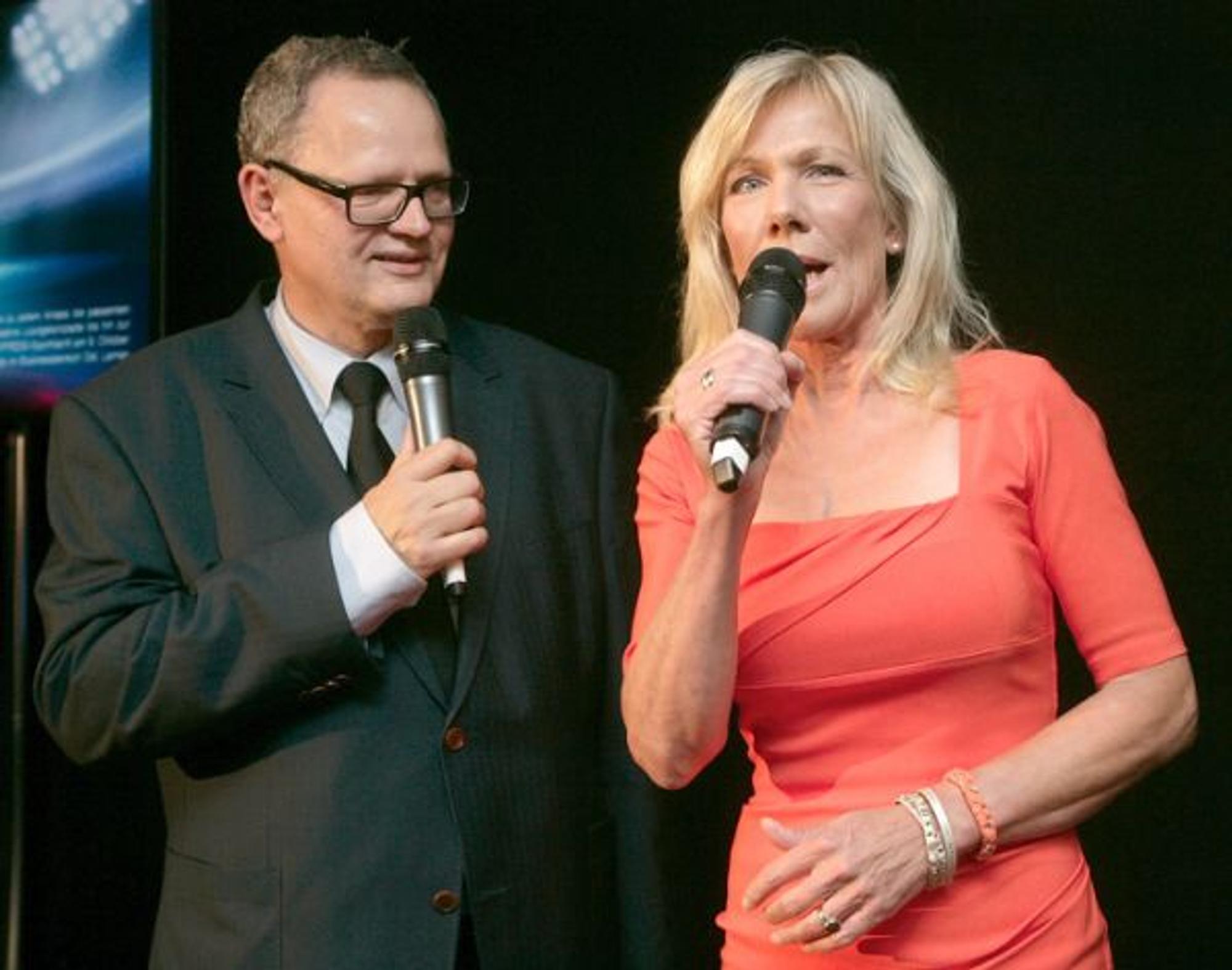 Ulli Potofski und Ulrike von der Groeben stehen als Moderations-Duo mit Mikros nebeneinander.