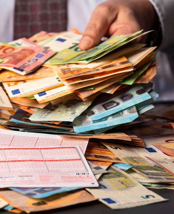 West-Lotto sucht verzweifelt einen Gewinner oder eine Gewinnerin aus NRW. Das Symbolfoto zeigt Lottoscheine und einen Mann mit Bargeld.