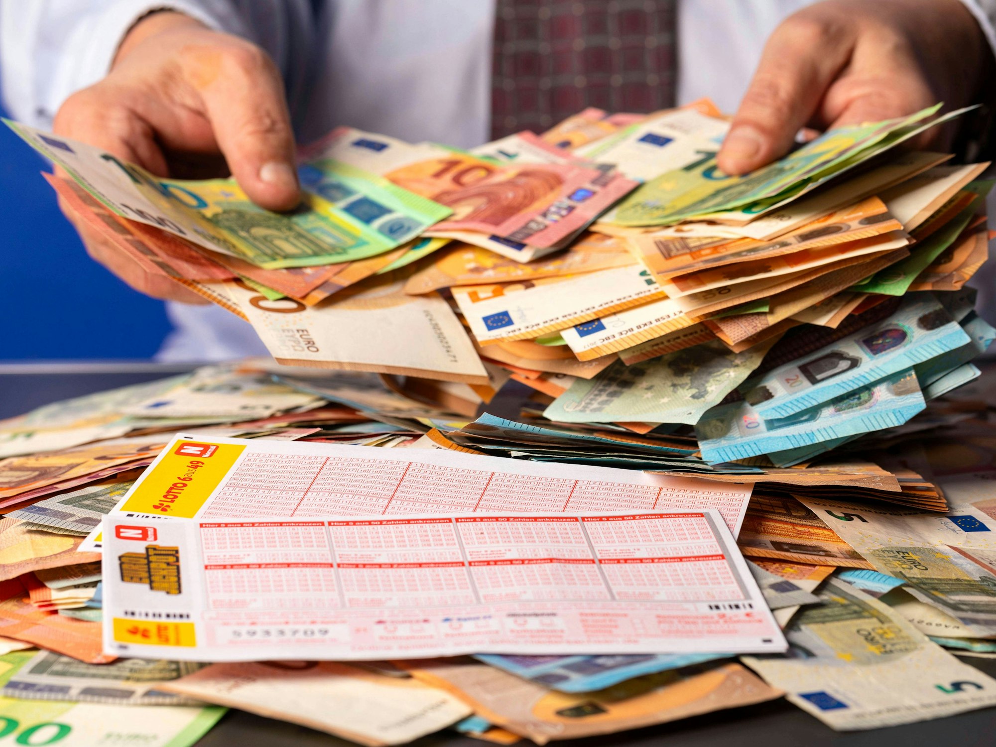 West-Lotto sucht verzweifelt einen Gewinner oder eine Gewinnerin aus NRW. Das Symbolfoto zeigt Lottoscheine und einen Mann mit Bargeld.