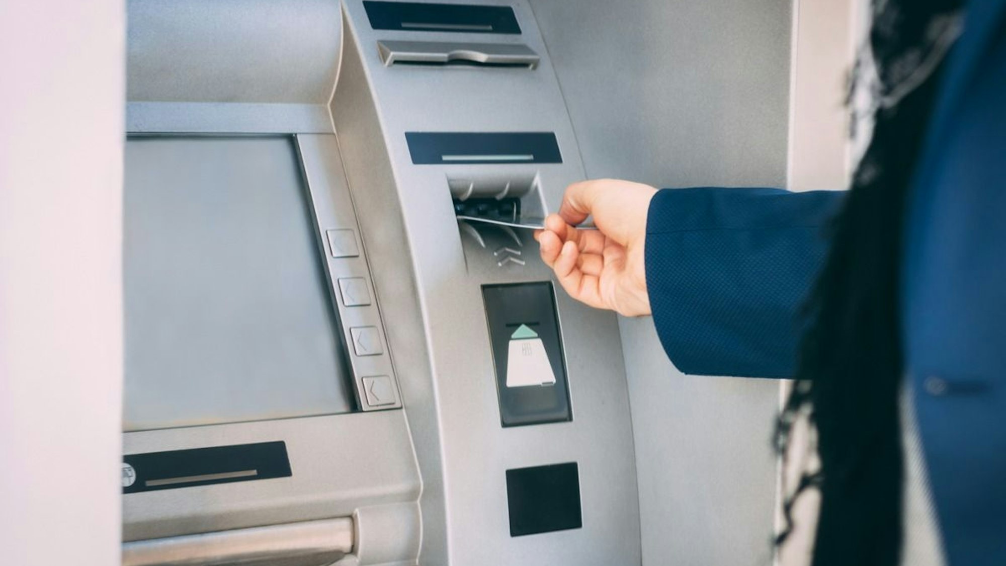Eine Person hebt Geld an einem Geldautomaten ab.
