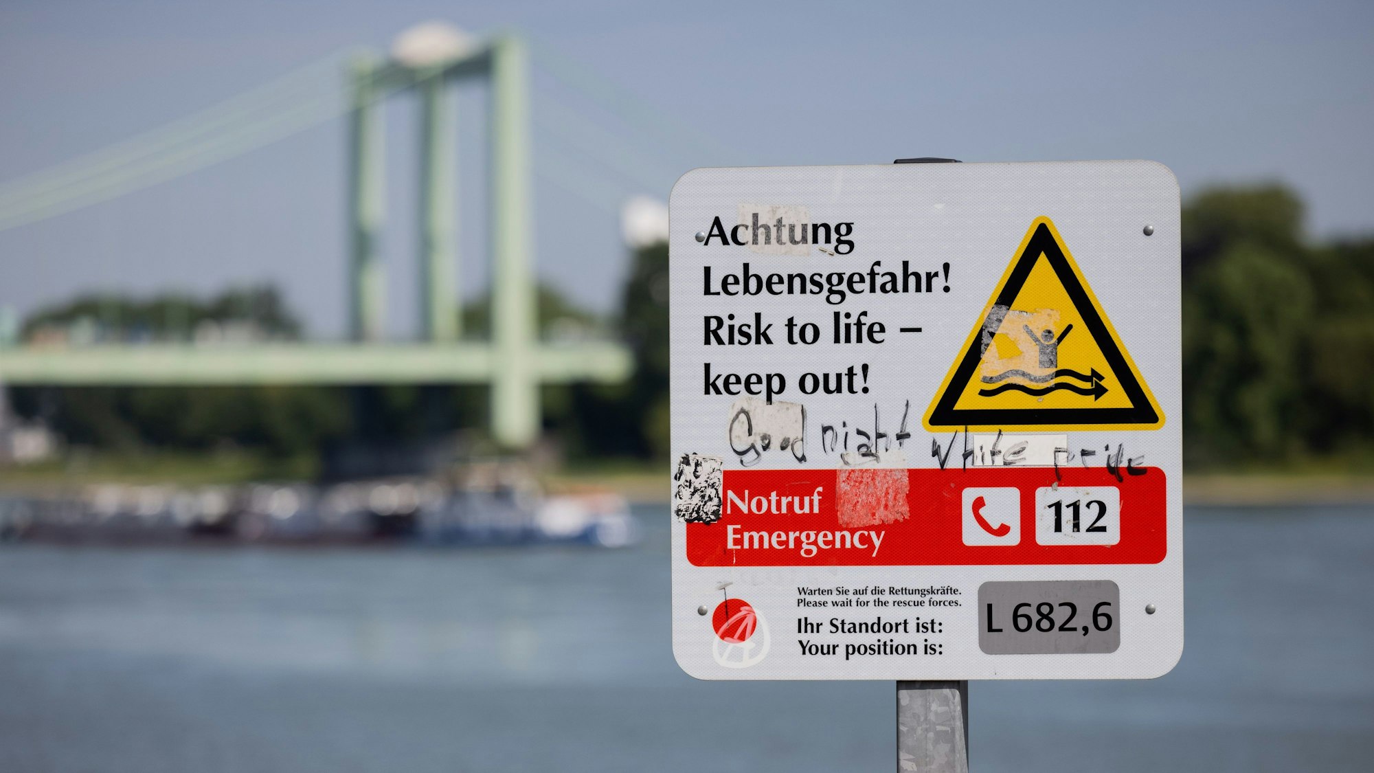 Ein Hinweisschild mit der Aufschrift „Achtung Lebensgefahr“ weist am Rhein in Rodenkirchen auf die Gefahren beim Schwimmen in dem Fluss hin.