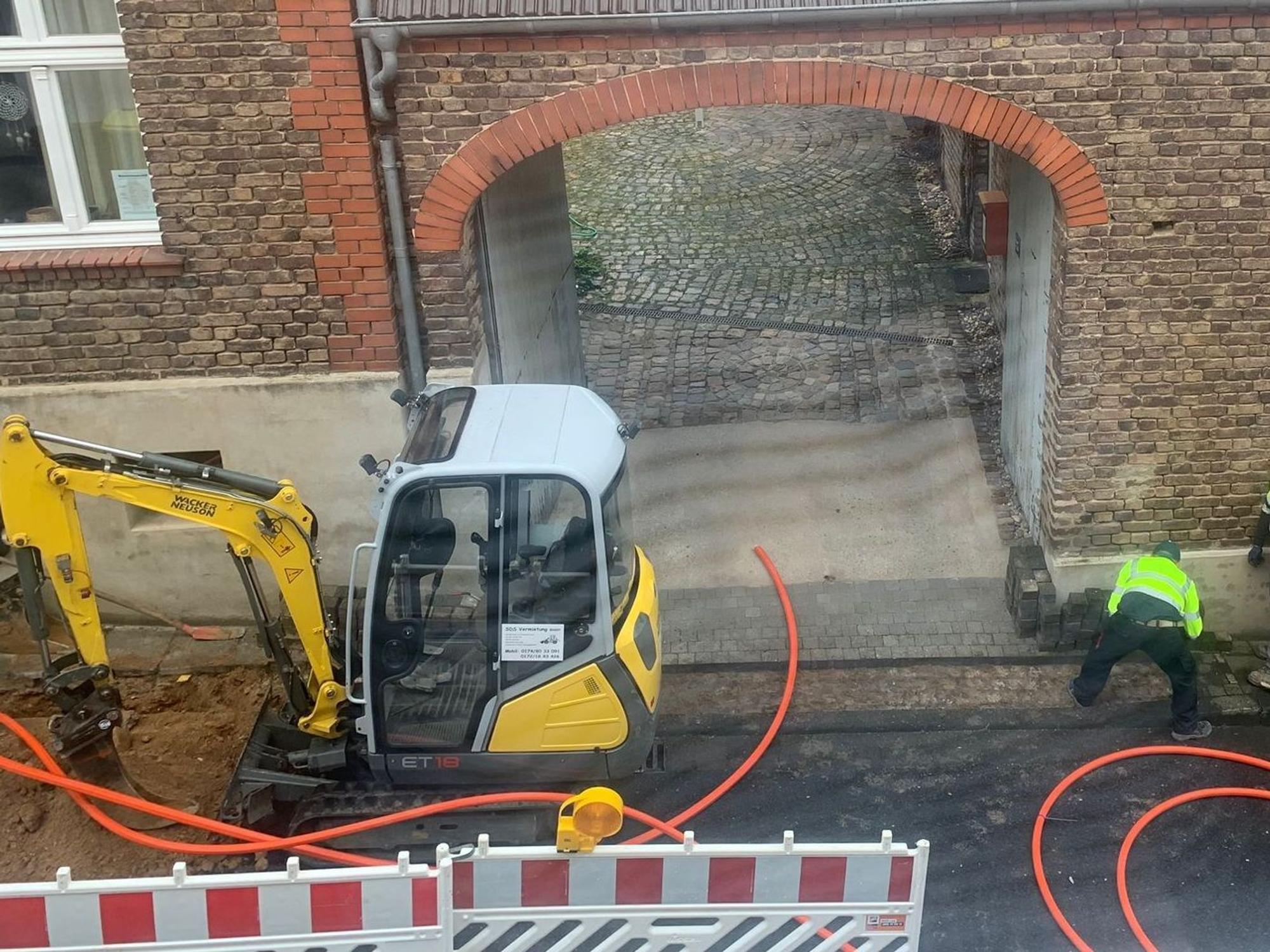 Ein Bagger steht auf einer Baustelle vor einem Altbau