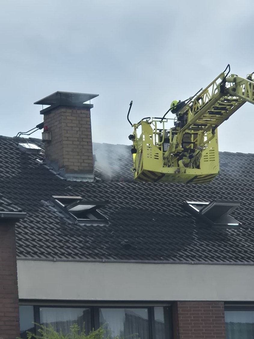 Feuerwehrleute auf einer Drehleiter vor einem Hausdach.