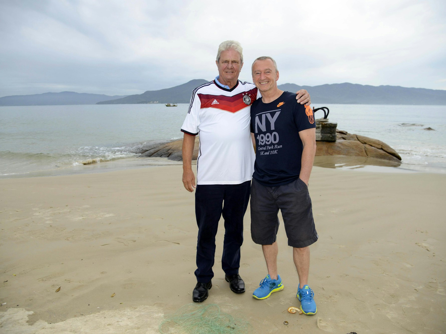 Dietmar Hopp und Spielerberater Roger Wittmann posieren Arm in Arm an einem Strand in Brasilien.