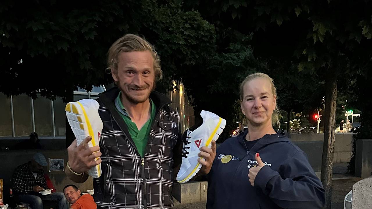 Ein Mann hält Sneaker in den Händen und grinst, neben ihm steht eine Frau.