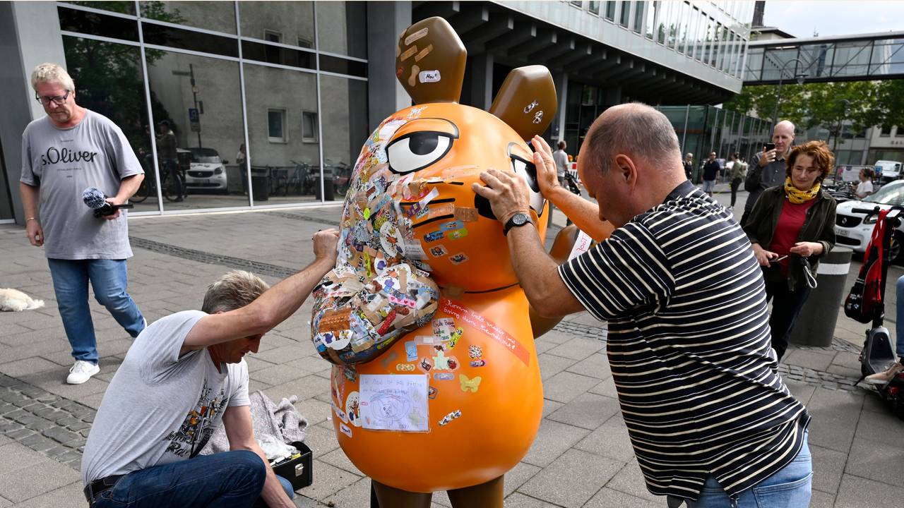 Zwei Mitarbeiter des Westdeutschen Rundfunks (WDR) schieben die etwa 75 Kg schwere Fiberglasskulptur der WDR-Maus zum Senderhaus. Die orangefarbene Maus-Figur wurde bei einem Brandanschlag beschädigt und wird nun repariert.