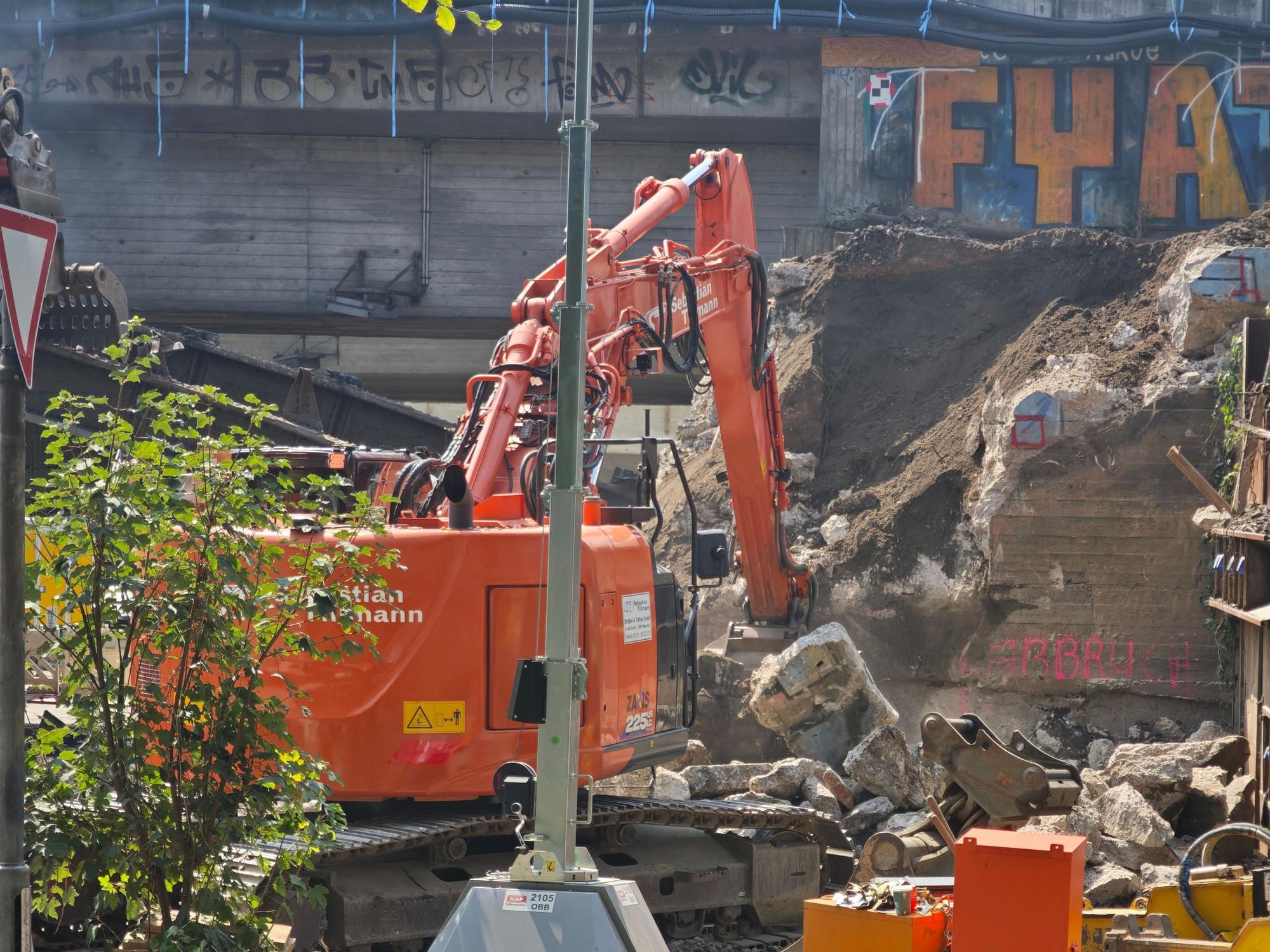 Ein Bagger reißt eine Brücke ein.