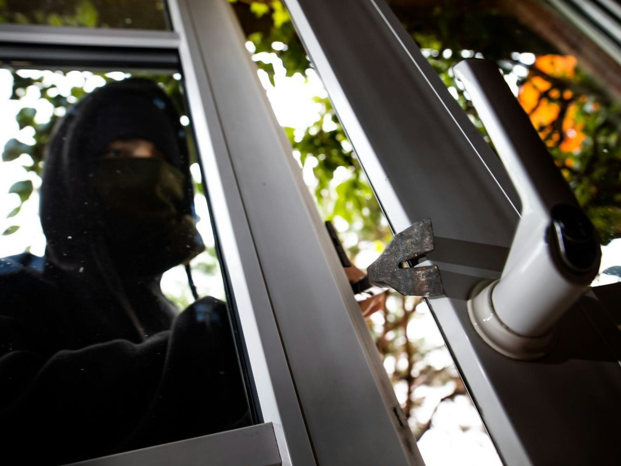 Eine maskierte Person öffnete eine Tür mit einem Brecheisen.