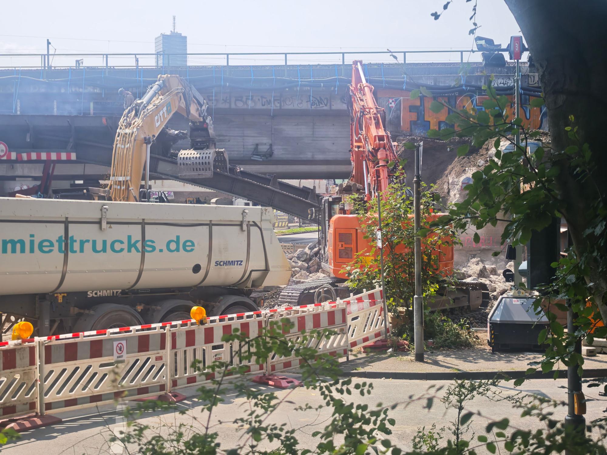 Ein Bagger trägt einen Stahlträger weg.
