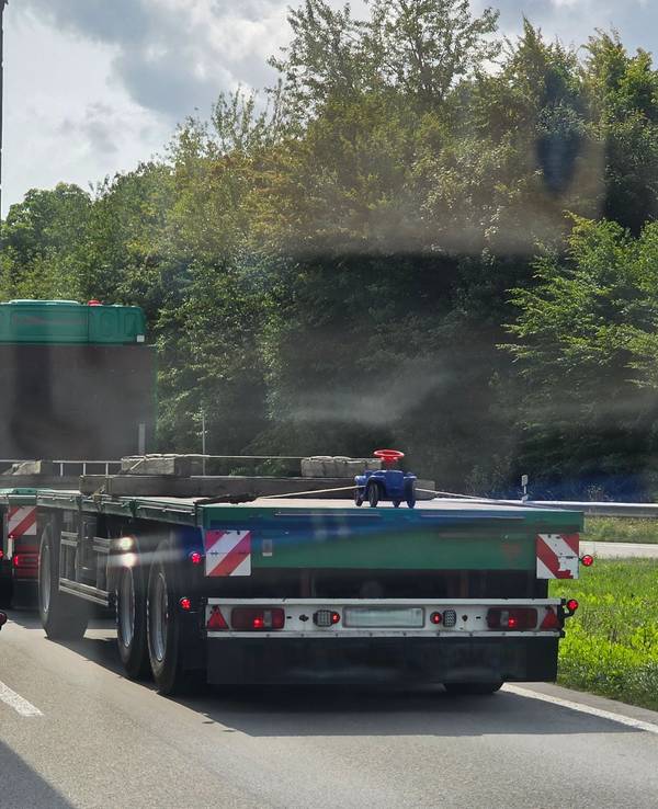 Auf der Ladefläche eines Lkw ist ein Bobbycar festgeschnallt.