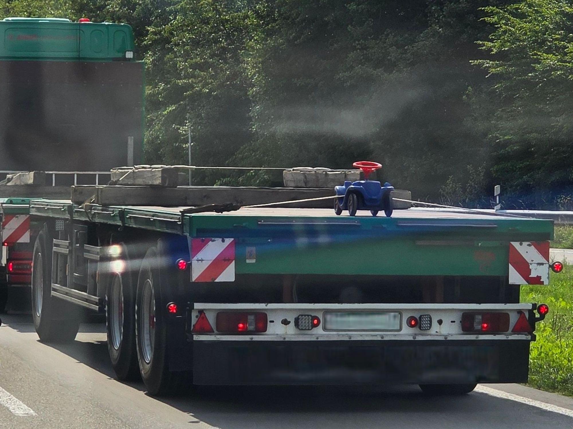 Auf der Ladefläche eines Lkw ist ein Bobbycar festgeschnallt.