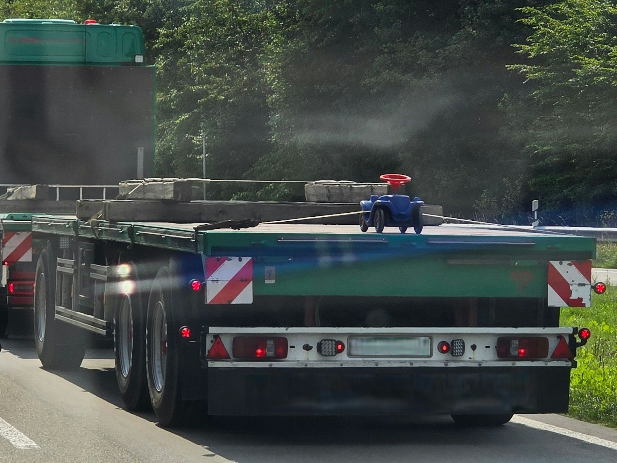 Auf der Ladefläche eines Lkw ist ein Bobbycar festgeschnallt.