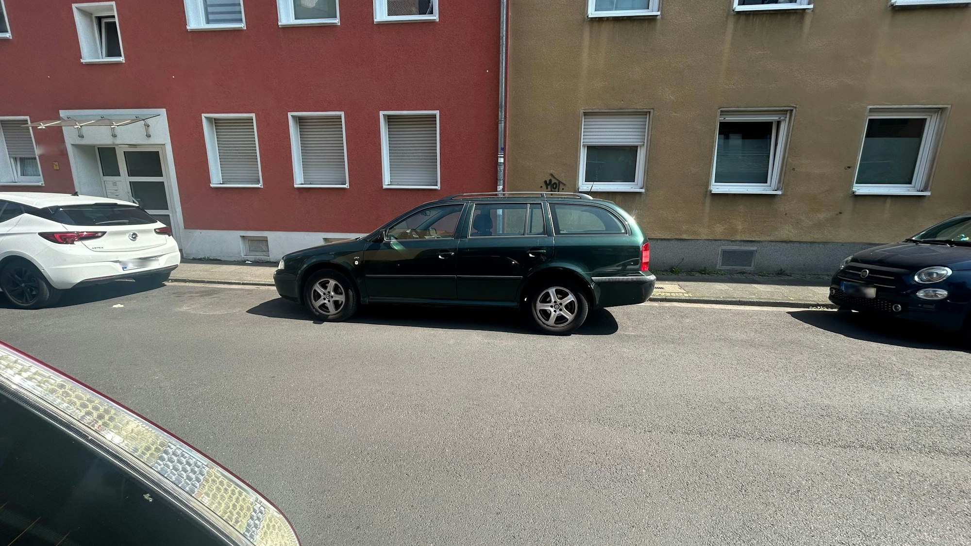 Ein Auto steht mit großem Abstand zu dem vorigen und dem hinteren Fahrzeug geparkt am Straßenrand.