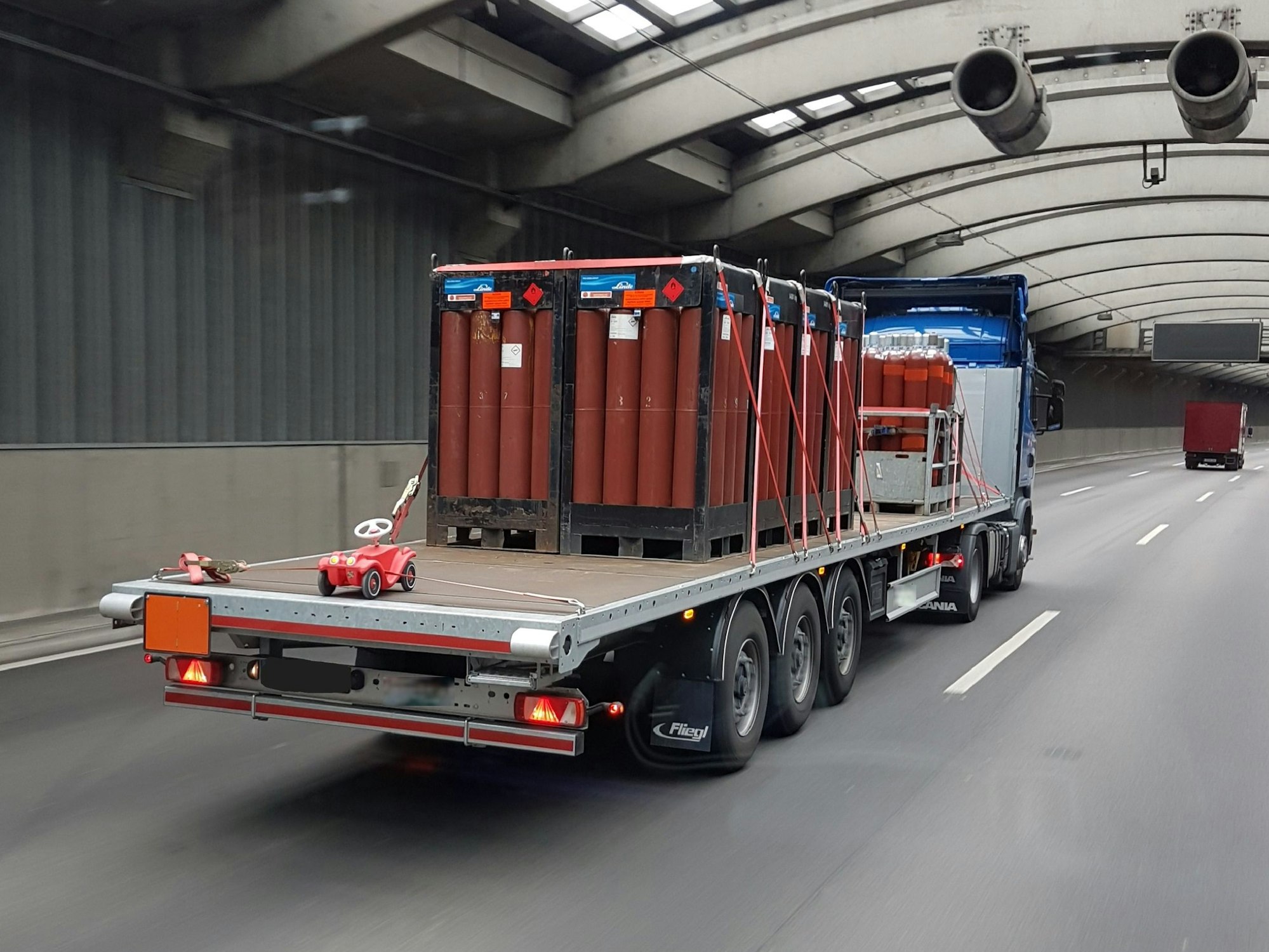 Auf einer Lkw-Ladefläche werden Gasflaschen und ein Bobbycar transportiert.