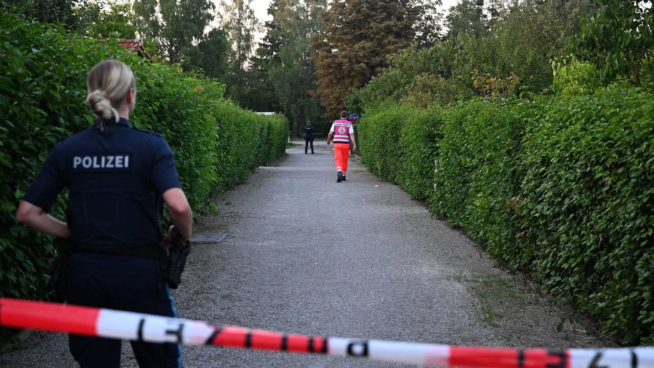 Die Polizei hat einen Gang in einer Kleingartenanlage abgesperrt. Hinter dem Flatterband steht eine Polizistin, weiter entfernt gegen ein Mann vom Rettungsdienst.
