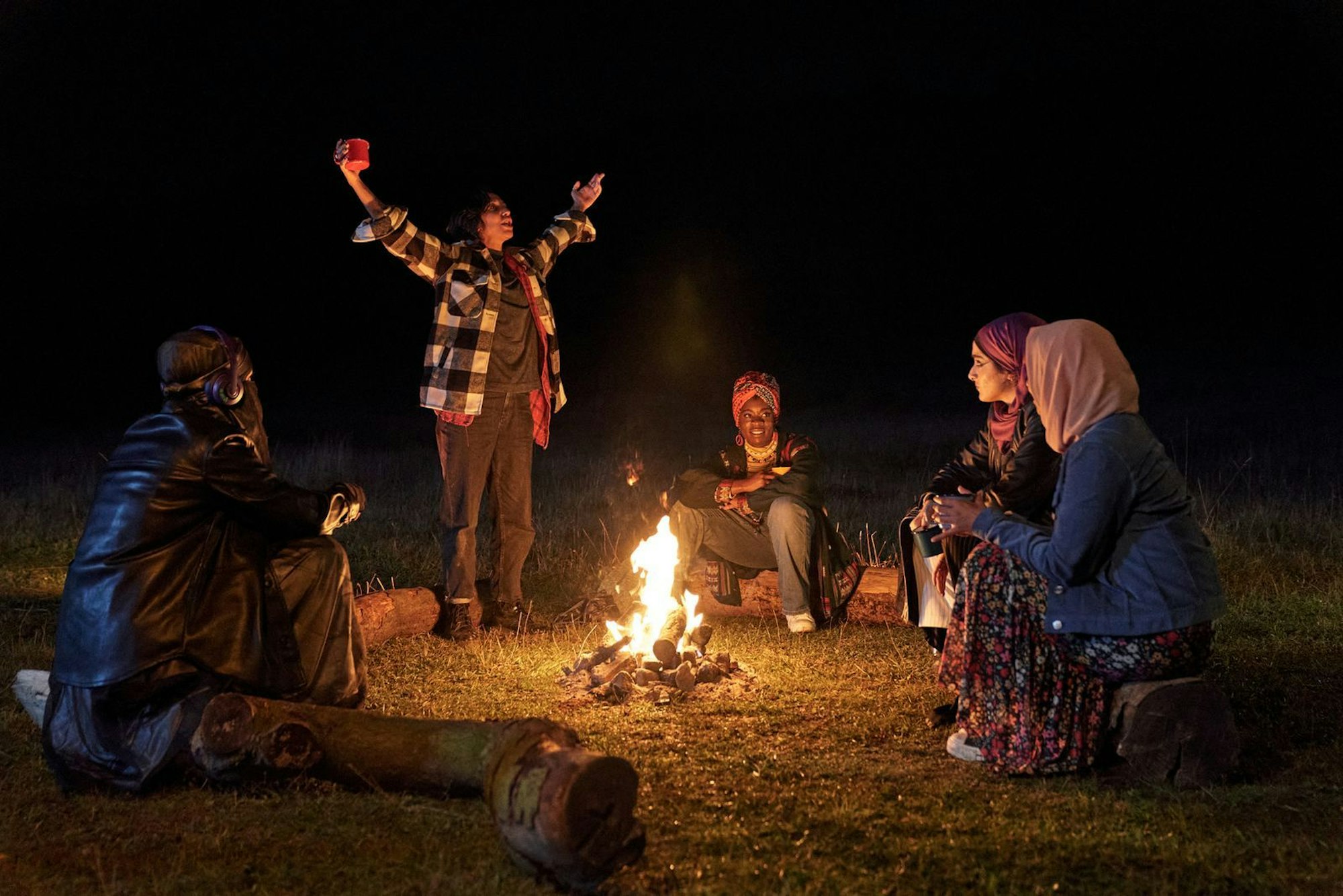 Am Lagerfeuer schöpfen Momtaz (Lucie Shorthouse), Saira (Sarah Kameela Impey), Bisma (Faith Omole), Ayesha (Juliette Motamed) und Amina (Anjana Vasan) neue Kraft für den Soundsmash-Vorentscheid (von links).
(Bild: ZDF/Laura Radford)