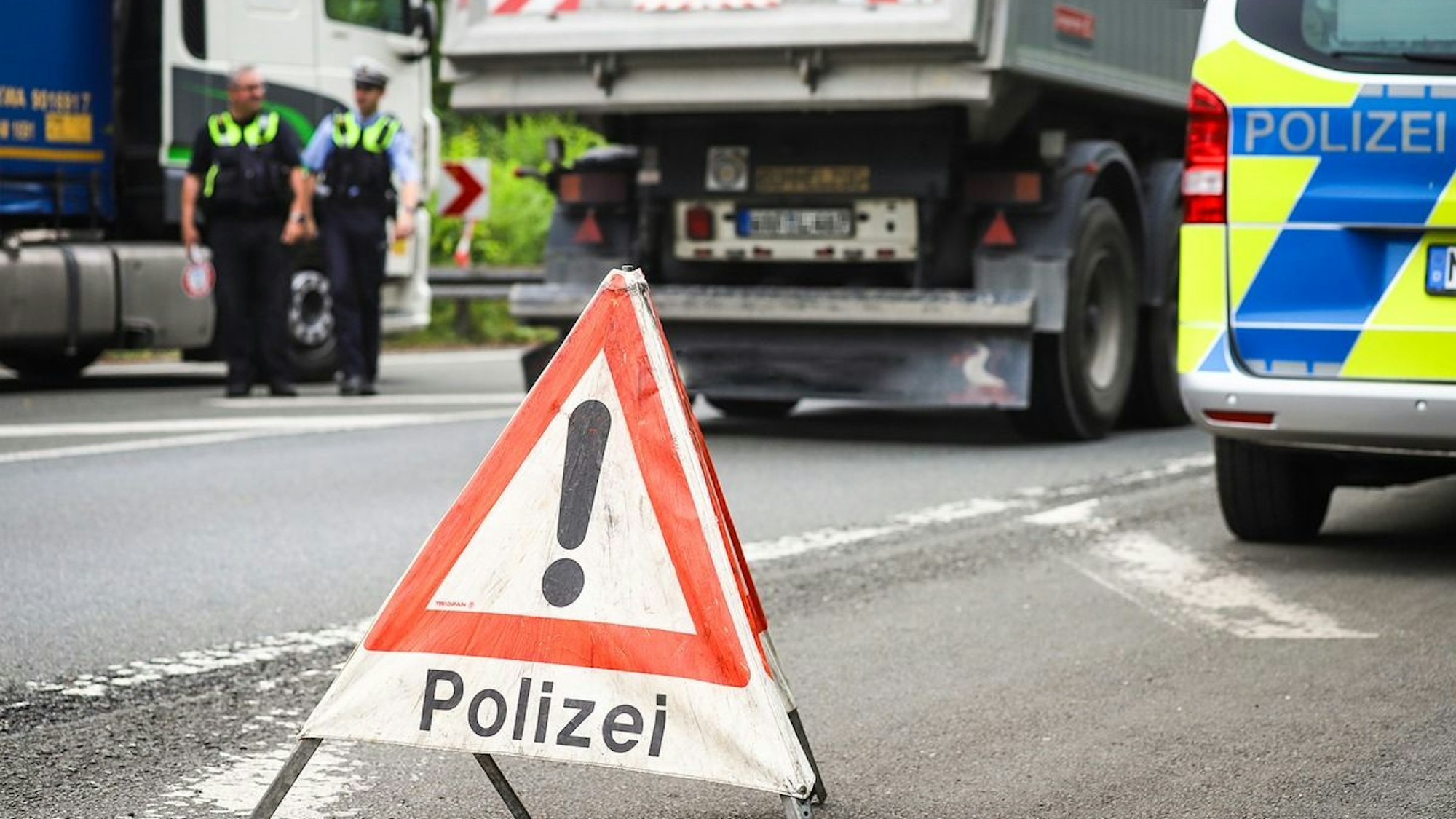 Ein Polizist führt eine Kontrolle an einem Lkw durch.