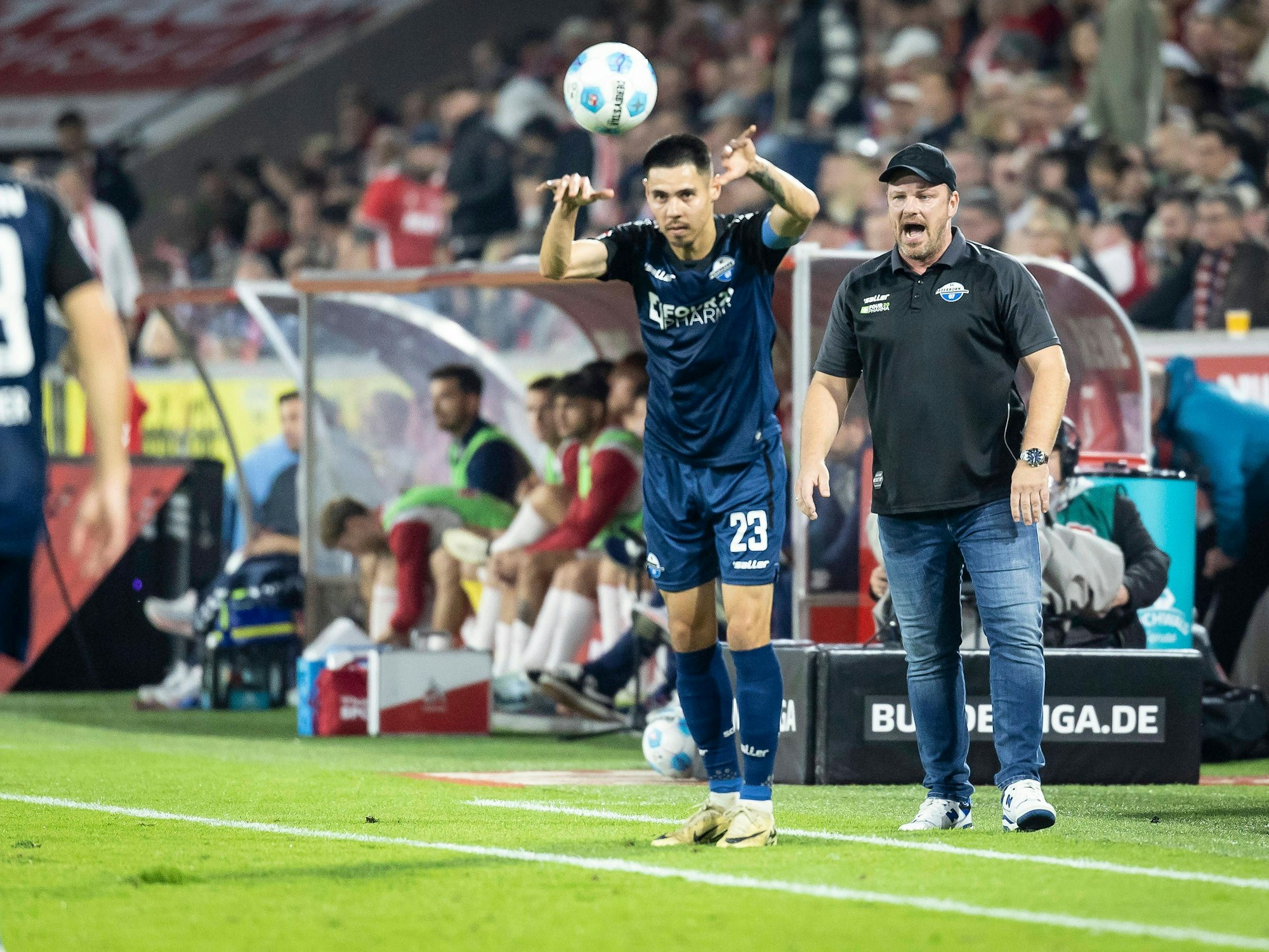 Raphael Obermair führt einen Einwurf aus, dahinter steht Lukas Kwasniok und brüllt.