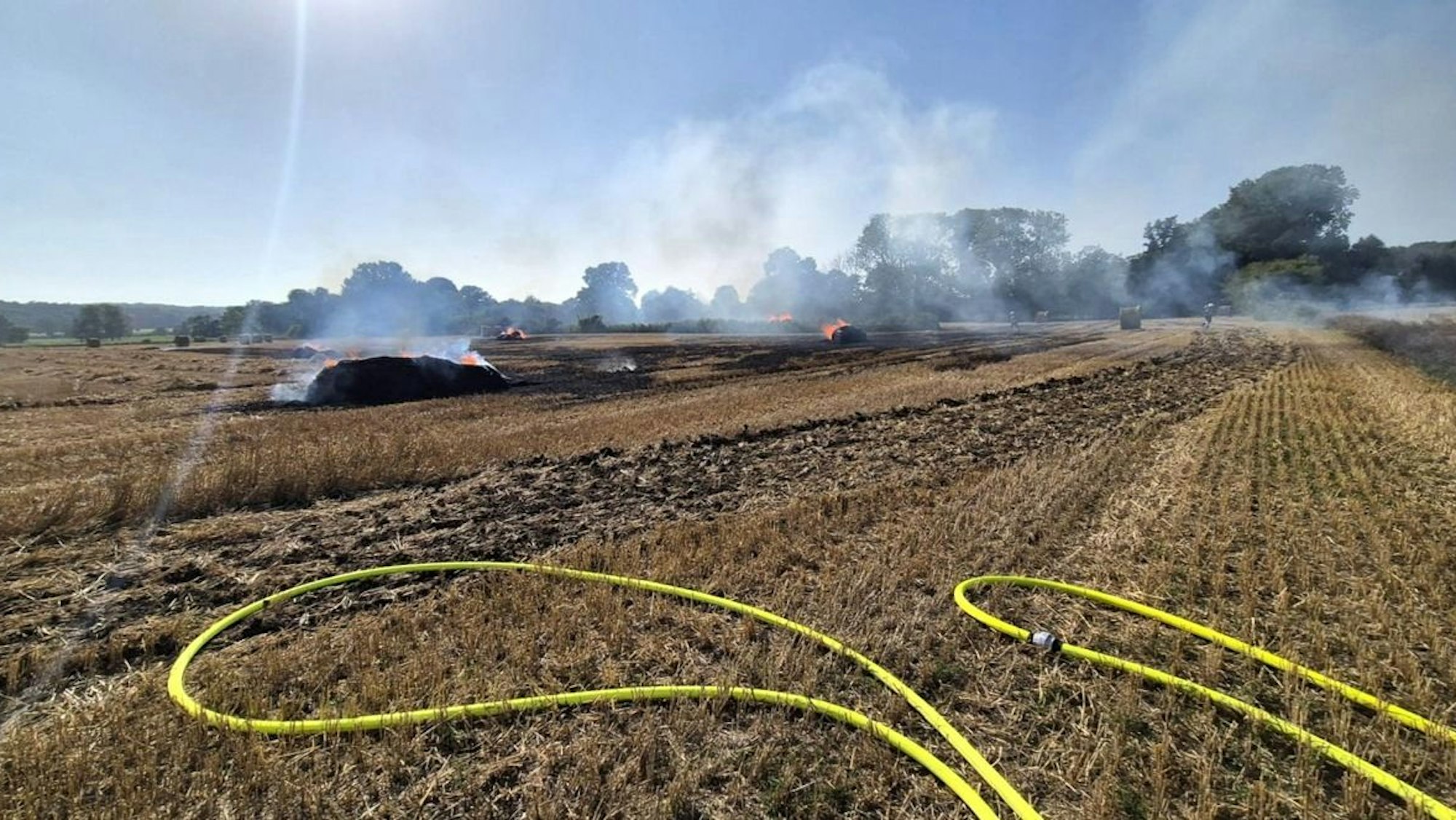 Eine brennende Strohpresse auf einem Feld.