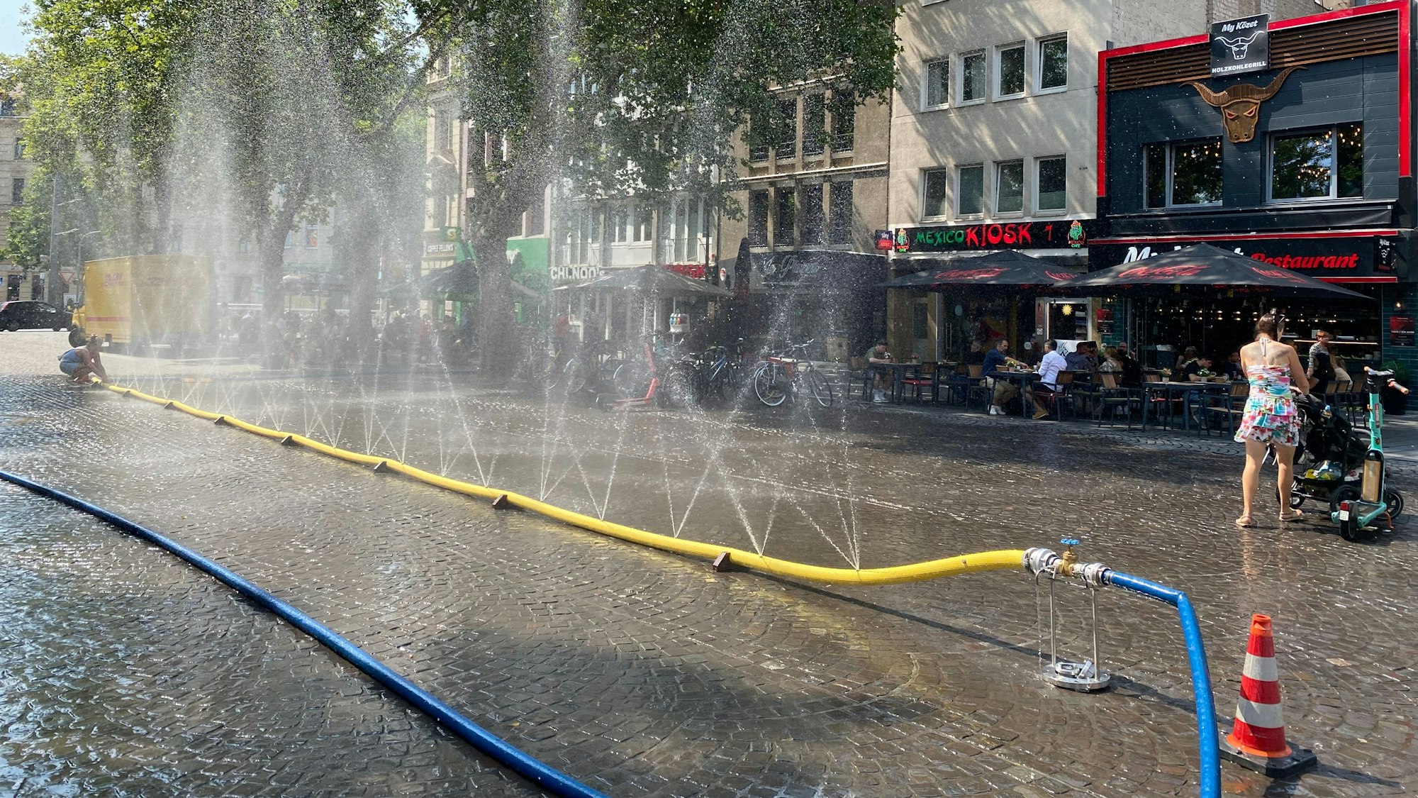 Aus einem Schlauch spritzen Wasserfontänen.