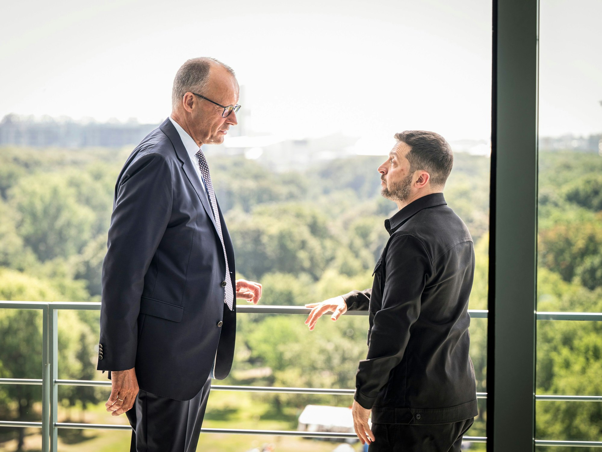 Bundeskanzler Friedrich Merz und Wolodymyr Selenskyj, Präsident der Ukraine, stehen am Geländer einer Terrasse und unterhalten sihc.