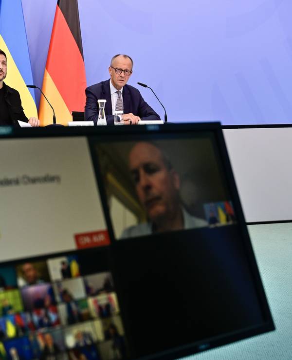 Wolodymyr Selenskyj, Präsident der Ukraine, und der deutsche Bundeskanzler Friedrich Merz sitzen an einem Tisch, davor steht ein Bildschirm.