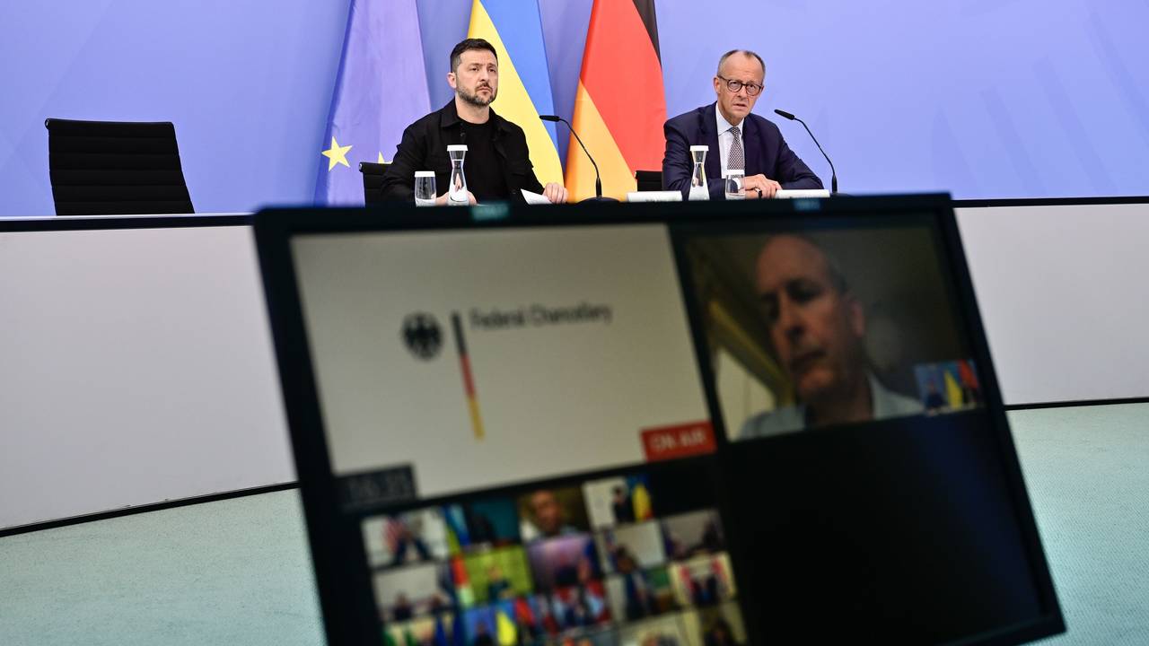 Wolodymyr Selenskyj, Präsident der Ukraine, und der deutsche Bundeskanzler Friedrich Merz sitzen an einem Tisch, davor steht ein Bildschirm.