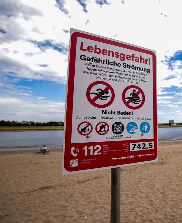 Ein Hinweisschild am Paradiesstand in Düsseldorf weist auf die Gefahren beim Schwimmen im Rhein hin. Ab Donnerstag gilt auch hier das Badeverbot.