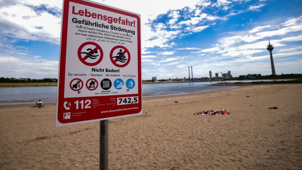 Ein Hinweisschild am Paradiesstand in Düsseldorf weist auf die Gefahren beim Schwimmen im Rhein hin. Ab Donnerstag gilt auch hier das Badeverbot.