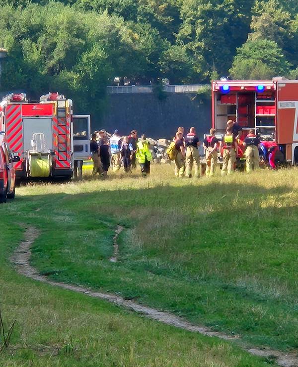 Einsatzfahrzeuge der Feuerwehr und des Rettungsdienstes sowie mehrere Einsatzkräfte stehen an einem Fluss.