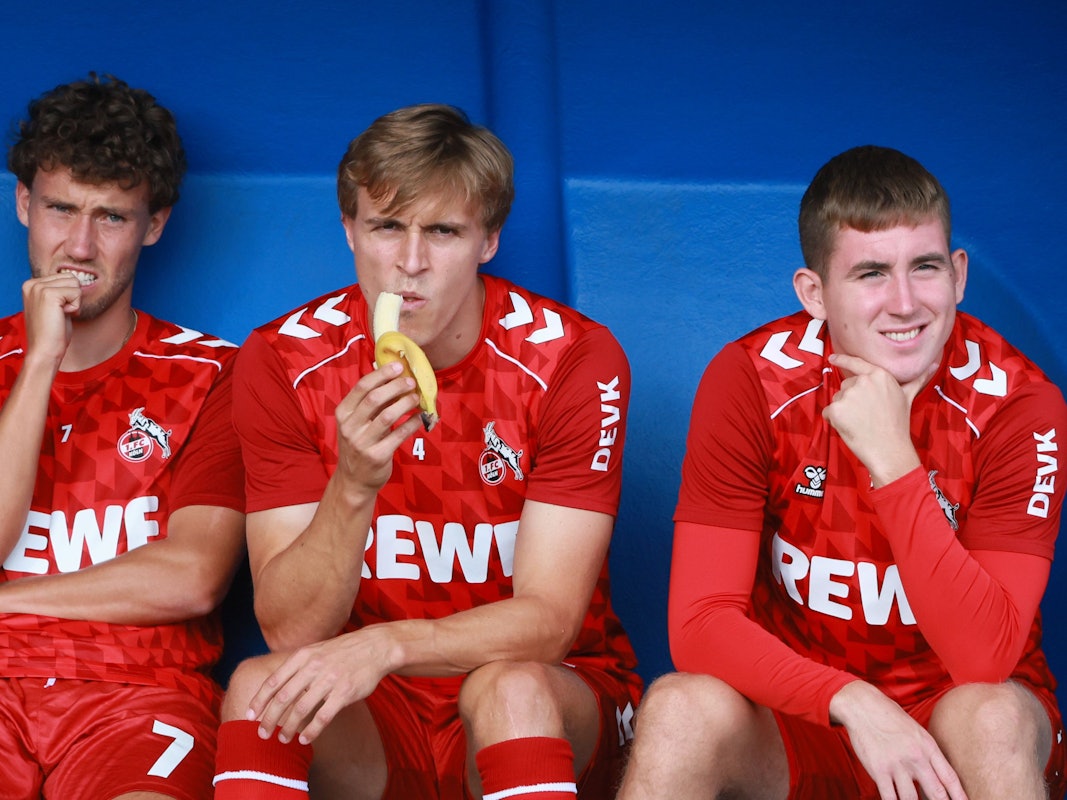 Timo Hübers sitzt auf der Bank zwischen Luca Waldschmidt und Isak Johannesson und isst eine Banane.