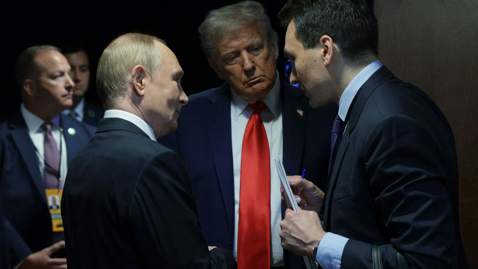 Auf diesem von der russischen Staatsagentur Sputnik verbreiteten Foto sprechen US-Präsident Donald Trump (Mitte) und der russische Präsident Wladimir Putin (links) nach einer gemeinsamen Pressekonferenz im Anschluss an ein Gipfeltreffen zwischen den USA und Russland in Alaska.