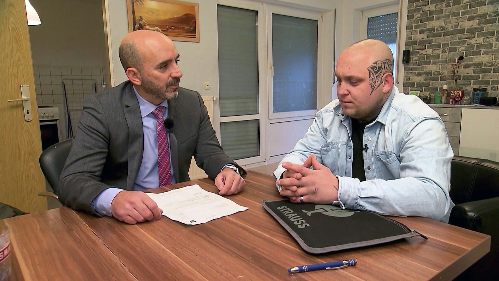 Max Postulka sitzt mit einem Mann am Tisch