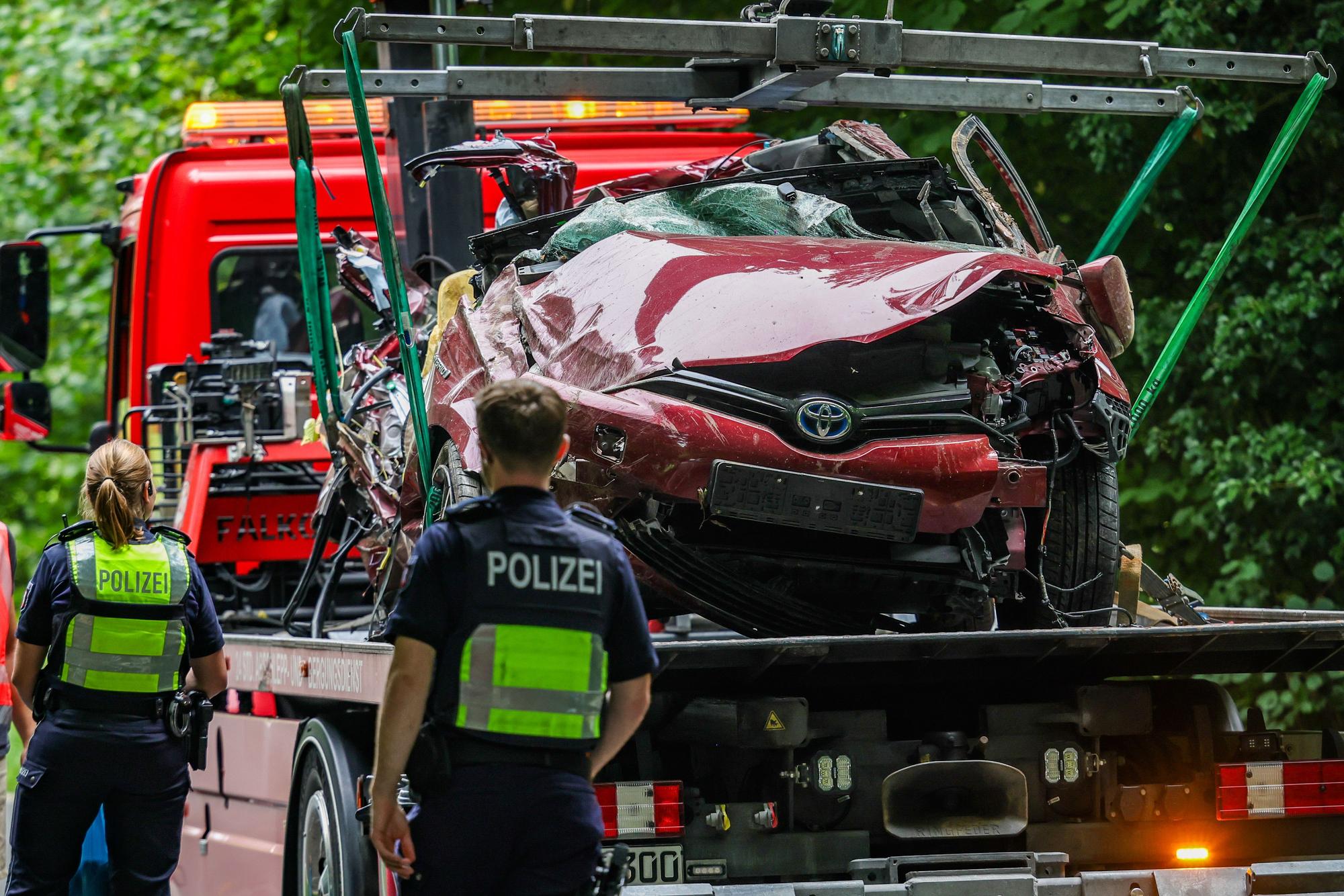 Das Autowrack steht nach der Bergung auf einem Abschleppfahrzeug, Polizeibeamte schauen sich das Fahrzeug an.