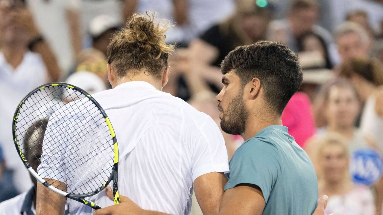 Carlos Alcaraz steht neben Alexander Zverev am Netz und nimmt ihn in den Arm.
