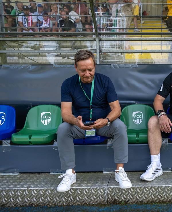Horst Heldt und Steffen Baumgart sitzen nebeneinander auf der Bank.