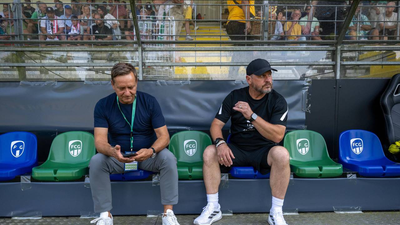 Horst Heldt und Steffen Baumgart sitzen nebeneinander auf der Bank.