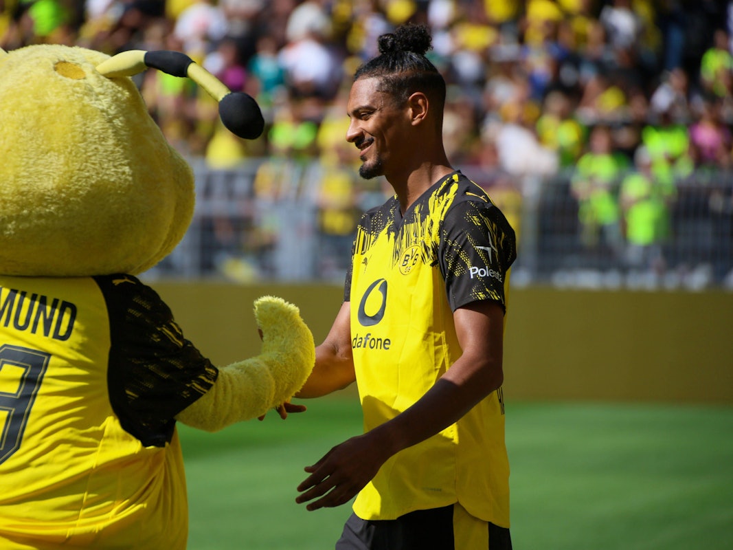 Sebastien Haller schlägt mit BVB-Maskottchen Emma, einer Biene, ein.