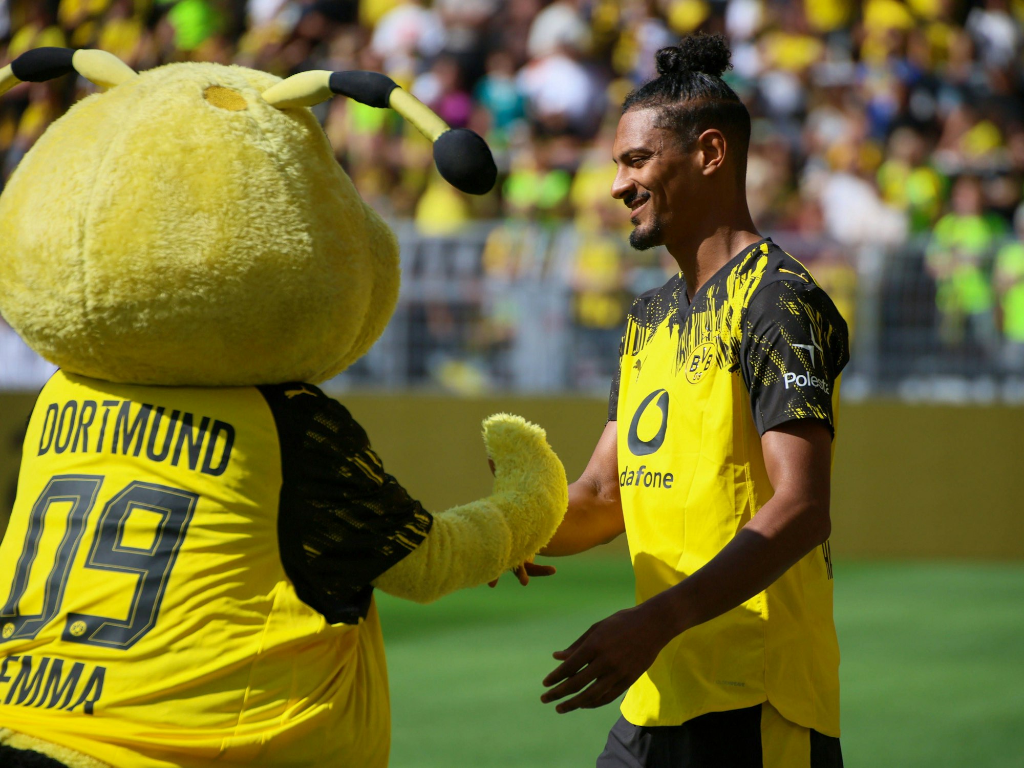 Sebastien Haller schlägt mit BVB-Maskottchen Emma, einer Biene, ein.