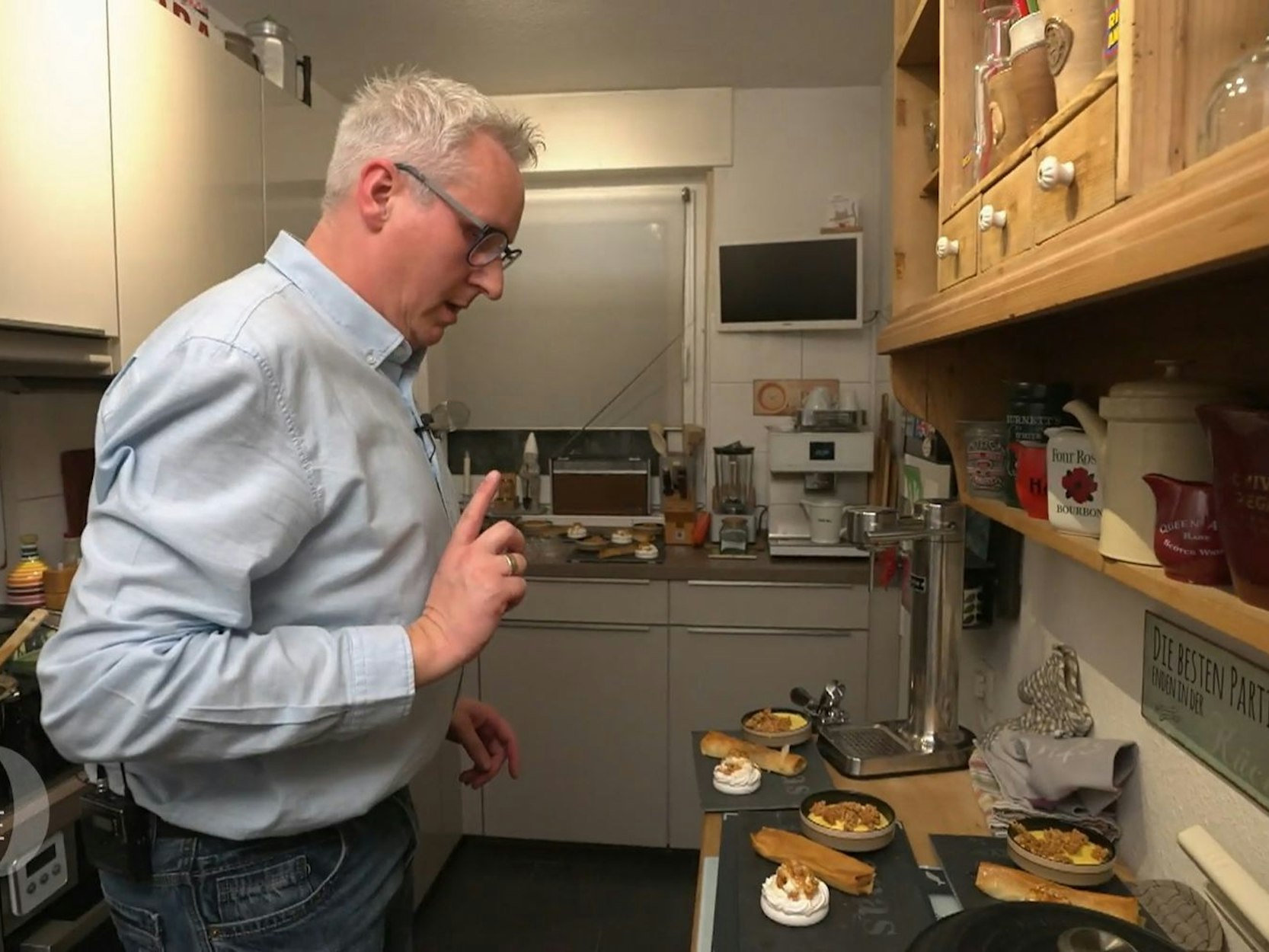 Ein Mann steht in der Küche und guckt sich seine Dessert-Kreationen an.