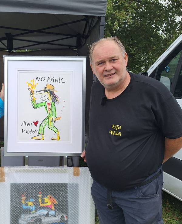 Zwei Männer halten ein Gemälde hoch, das einen tanzenden Mann mit Hut zeigt.