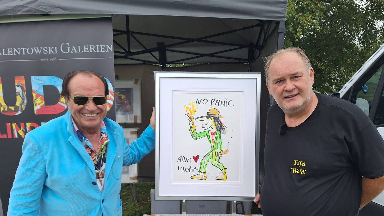 Zwei Männer halten ein Gemälde hoch, das einen tanzenden Mann mit Hut zeigt.