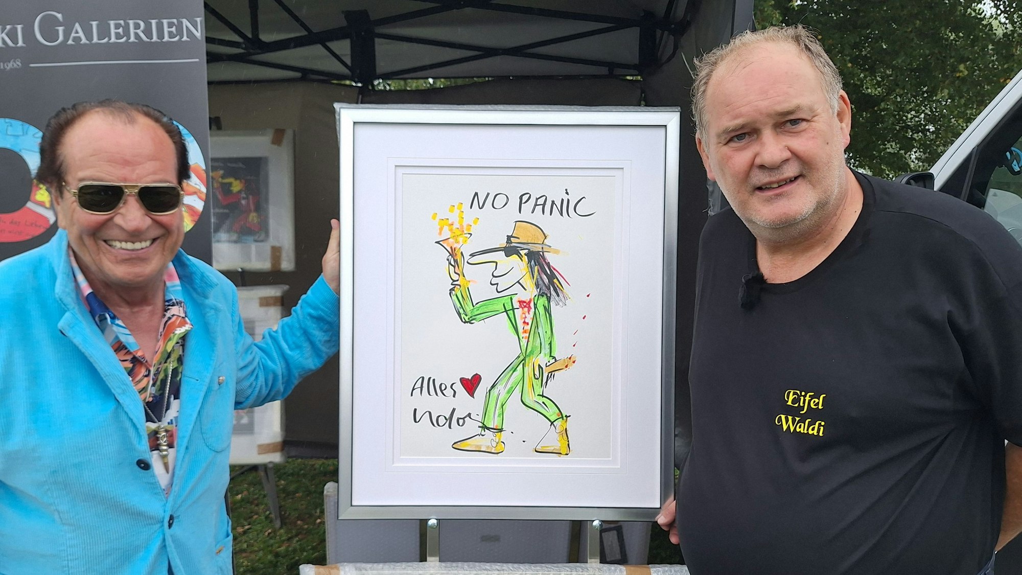 Zwei Männer halten ein Gemälde hoch, das einen tanzenden Mann mit Hut zeigt.