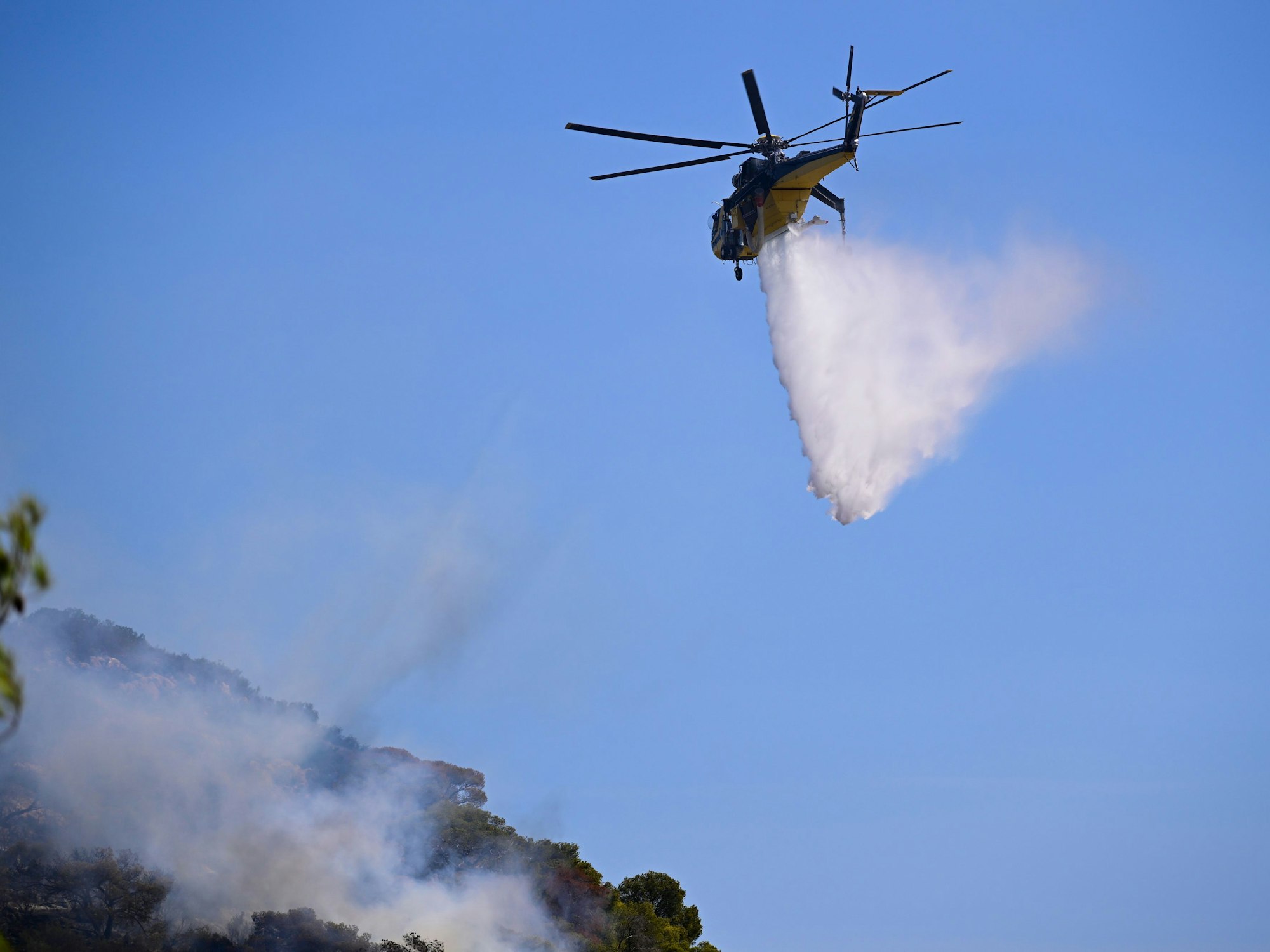 Ein Hubschrauber wirft Wasser ab.