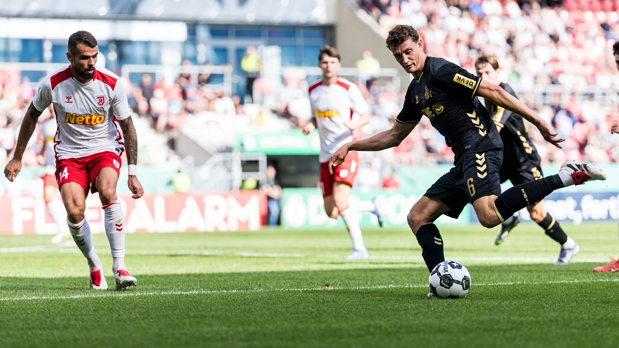 Robin Ziegele (SSV Jahn Regensburg) kommt beim Schuss von Kölns Eric Martel (r.) zu spät.