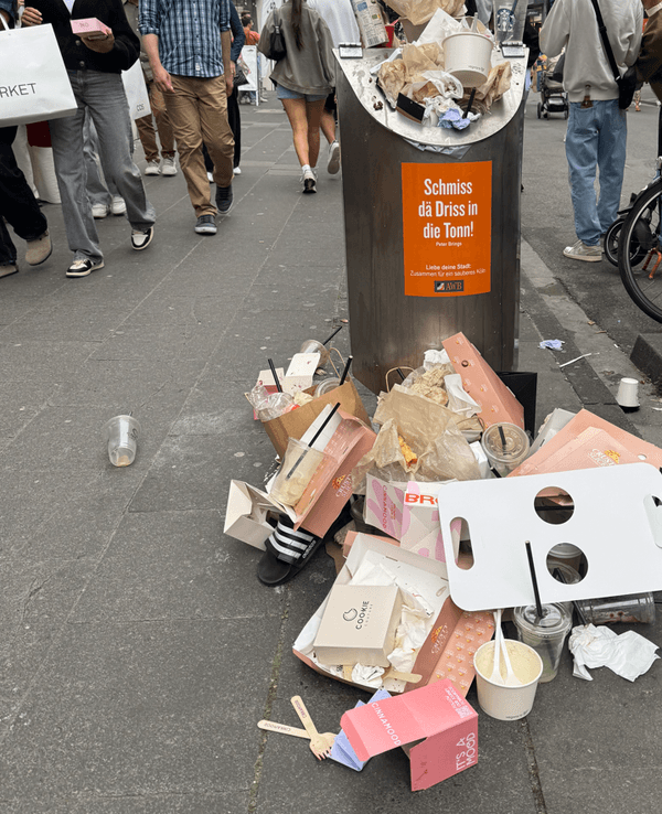 Vor einem Mülleimer stapelt sich Müll.